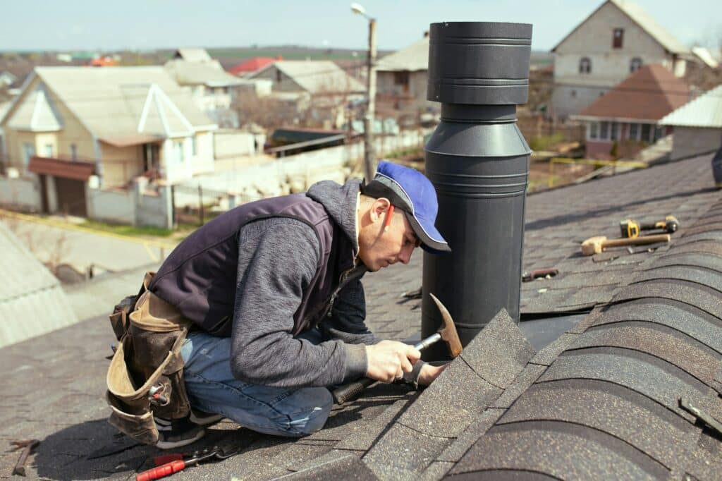 a professional master roofer with hammer repairs the roof.