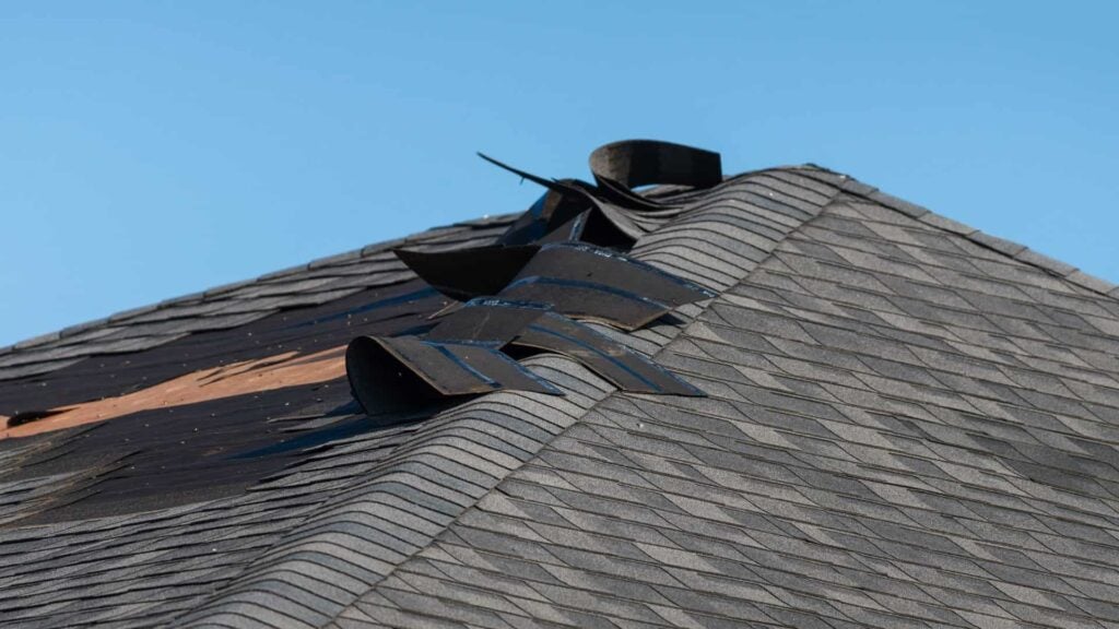 A roof that has wind damage and will require the owner to file an insurance claim for emergency roof repair